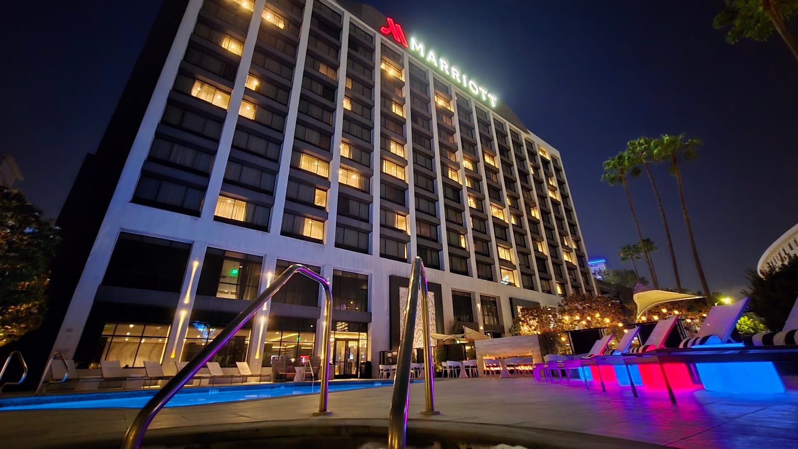 Illuminated outdoor pool deck and hotel facade at night
