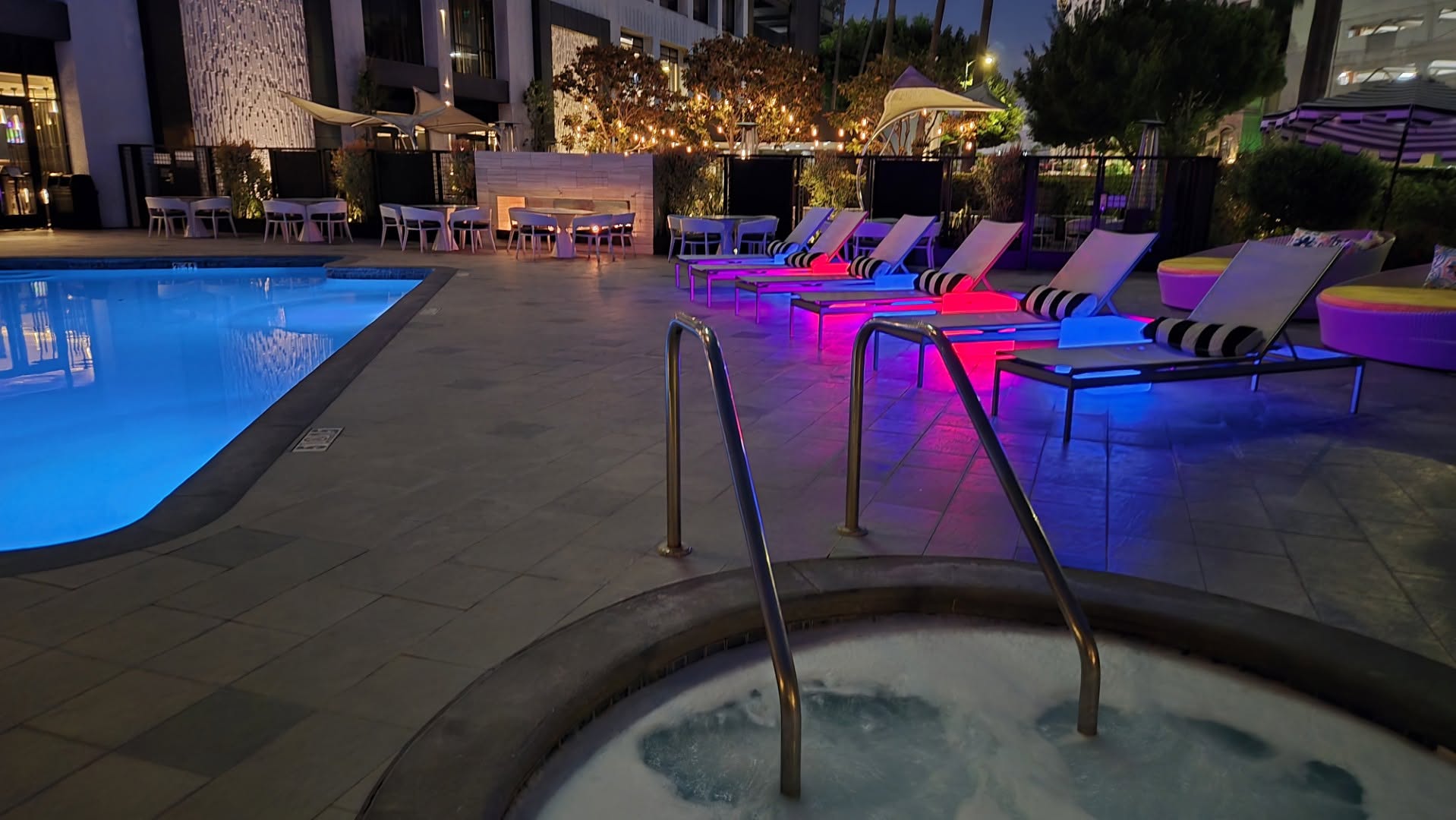 Bubbling whirlpool hot tub and glowing LED loungers at night